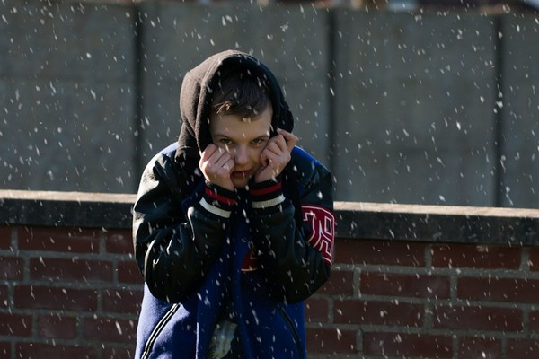 Ein Junge im Regen, der sich die Kapuze seiner Jacke schützend über den Kopf zieht. Foto: Pixabay