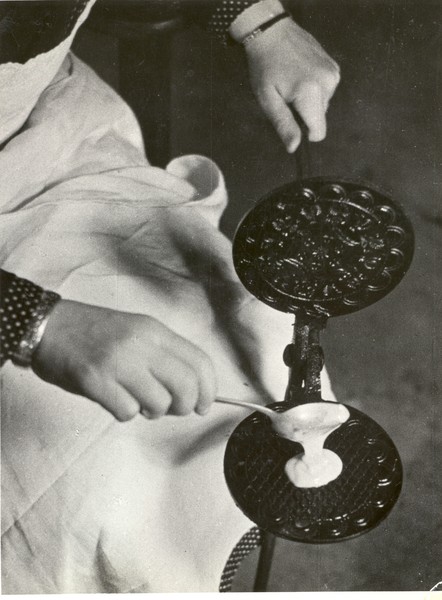 Eine Frau füllt mit einem Löffel Teig in ein Eiserkuchen-Eisen. Backen von Iserkoken in den 1950er/1960er Jahren in Westfalen. Foto: LWL-Archiv/Lindem