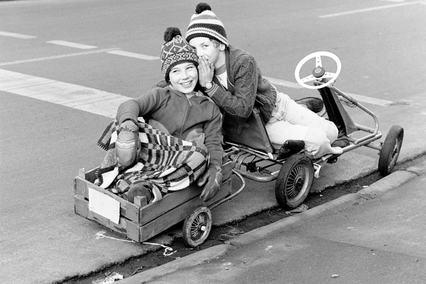 Jungen mit einem Kettcar (Tretauto/Gokart) der Firma Kettler samt Anhänger unterwegs. © LWL-Medienzentrum für Westfalen