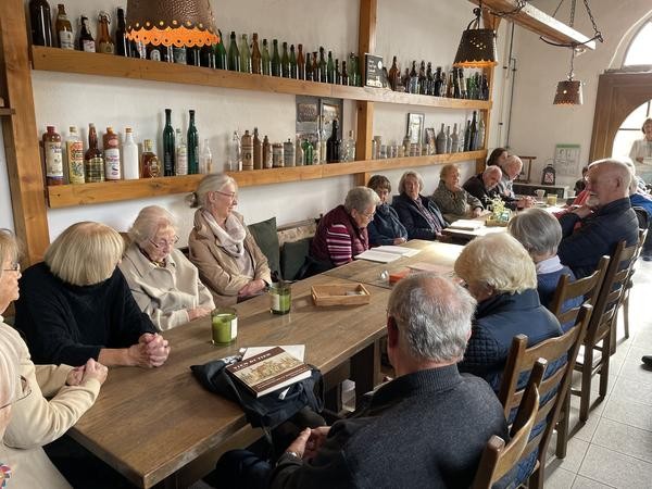 Zuhörer sitzen an einem Tisch und lauschen einer Lesung