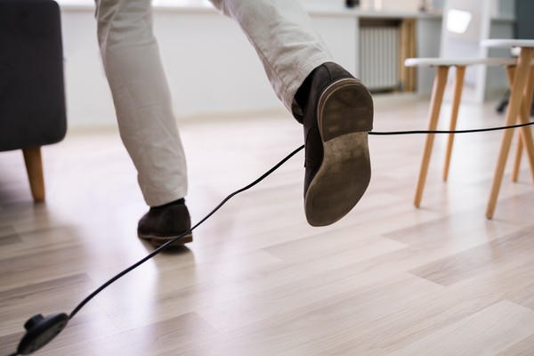 eine Person, die über ein Kabel im Weg stolpert und das Gleichgewicht verliert